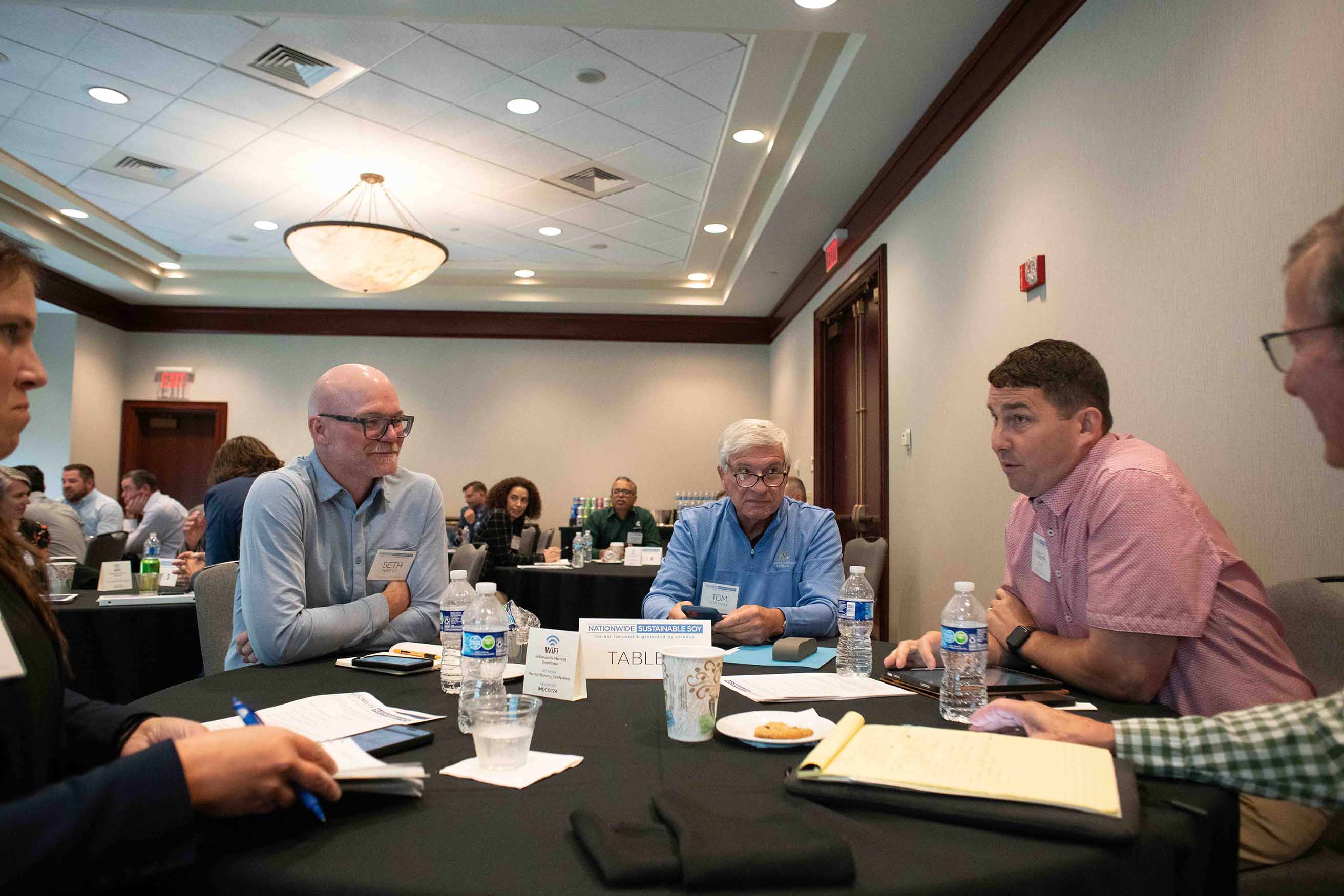 Attendees talk around a table during the Nationwide Sus