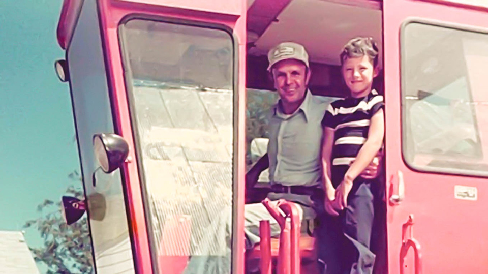 Farmer and child on red tractor