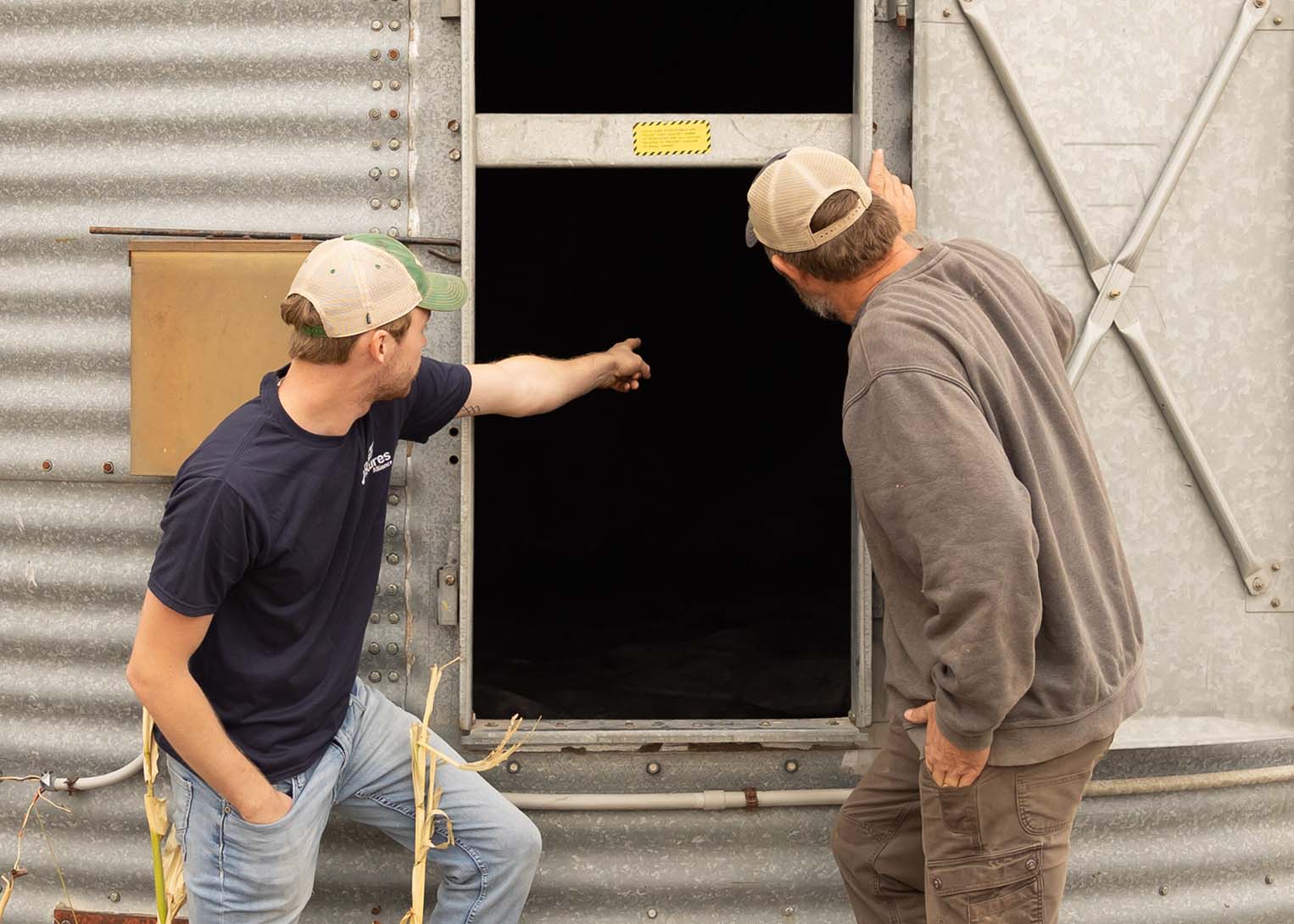 Son and father looking into grain bin