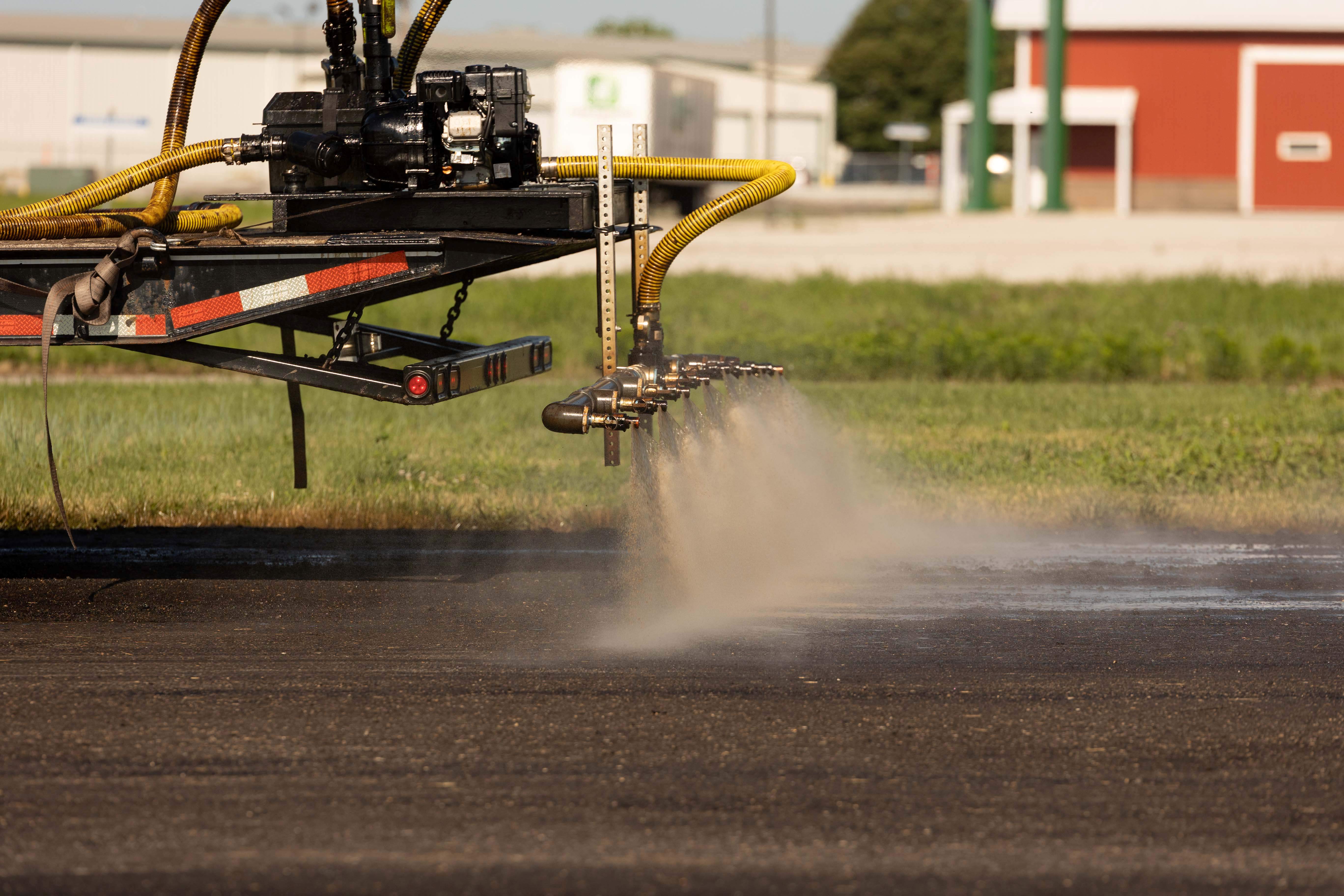 Truck spraying soy-based coating on asphalt