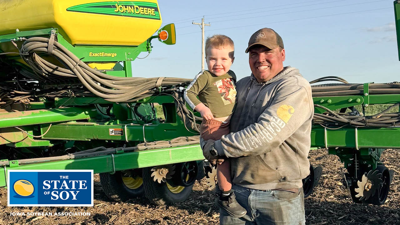 Farmer holds son in front of John Deere planter